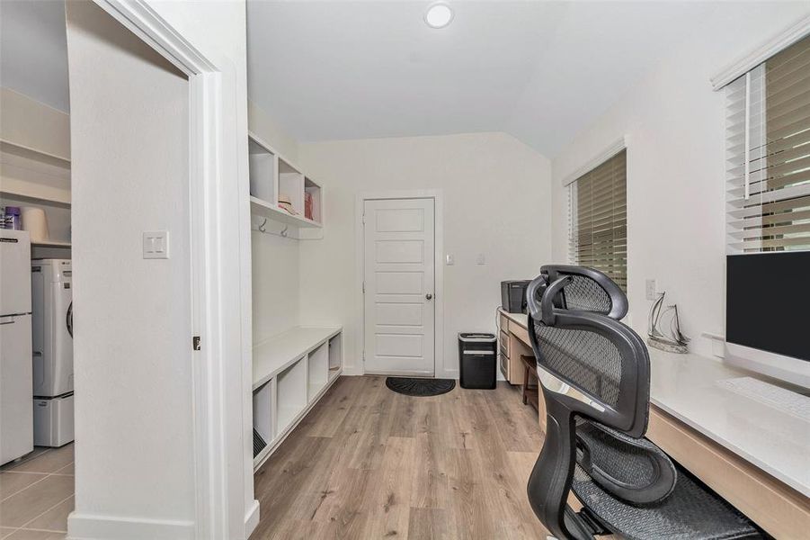 Home office with light hardwood / wood-style flooring, stacked washer / drying machine, vaulted ceiling, and a wealth of natural light