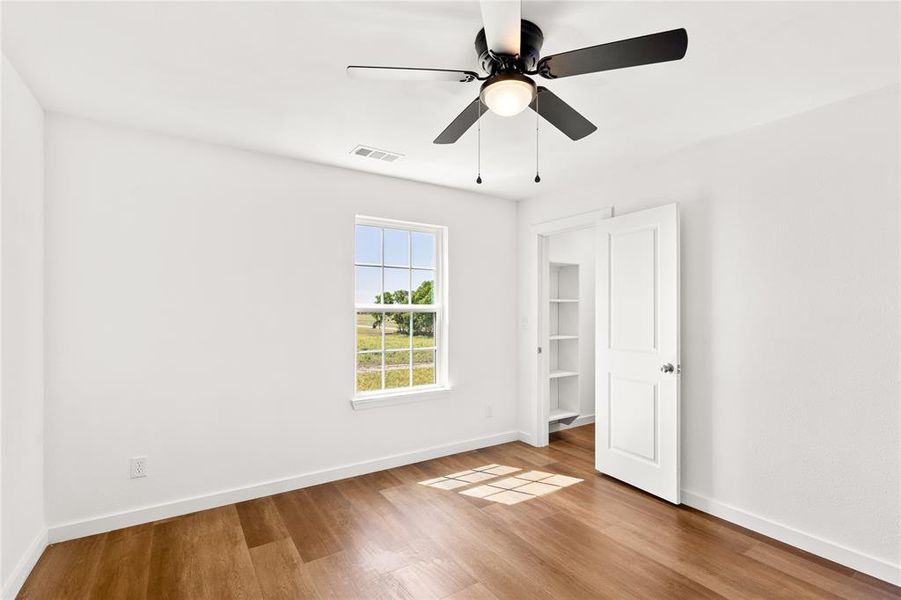 Bright interior space featuring wood-finish flooring, white walls, and a ceiling fan with integrated lighting