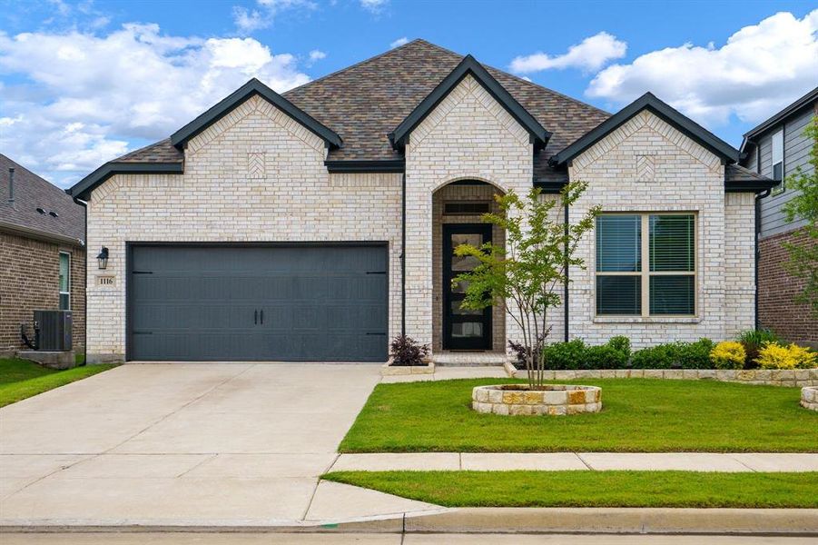 French provincial home featuring a front lawn, driveway, a garage, central AC unit, and brick siding French provincial home featuring a front lawn, driveway, a garage, central AC unit, and brick siding