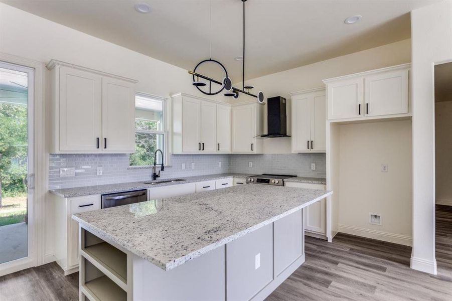 Kitchen with wall chimney exhaust hood, a sink, white cabinets, tasteful backsplash, and recessed lighting