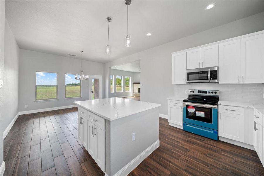 Kitchen with tasteful backsplash, a chandelier, white cabinets, a kitchen island, and stainless steel appliances