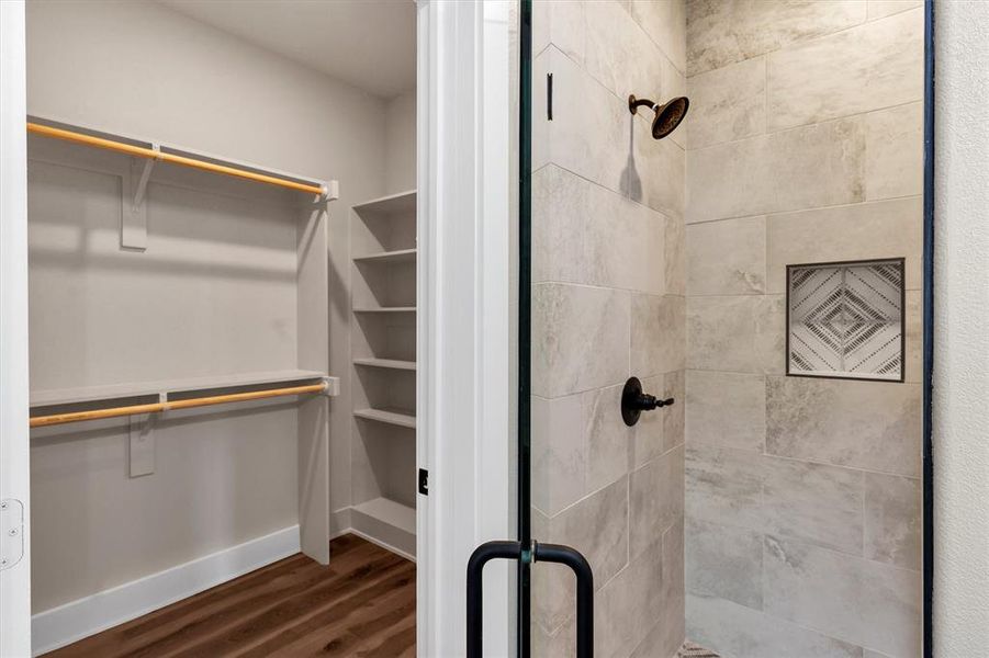 Bathroom featuring a stall shower, dark wood-type flooring, and a walk in closet Bathroom featuring a stall shower, dark wood-type flooring, and a walk in closet