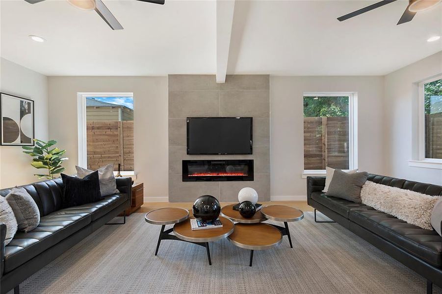 Living room with beamed ceiling, a tile fireplace, and ceiling fan