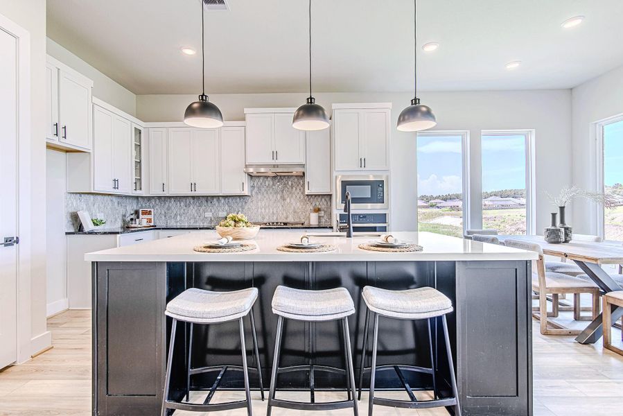 Gather in a chef’s kitchen that stuns with quartz countertops, white shaker cabinetry, and breathtaking views from the adjacent dining space.