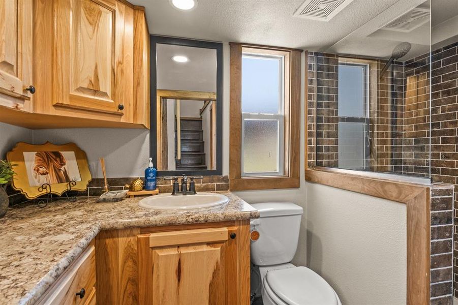 Full bathroom featuring vanity, tiled shower, and a textured ceiling