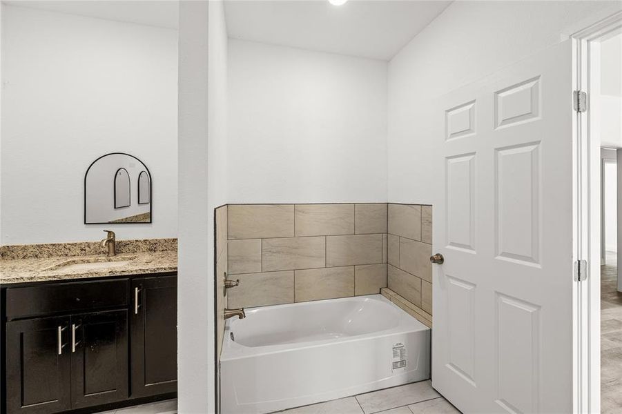 Bathroom with tile patterned floors, a tub to relax in, and vanity