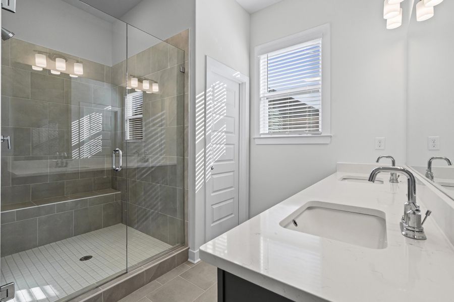 Bathroom featuring double vanity, a stall shower, and light tile patterned flooring