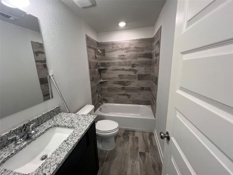 Modern bath offering sleek fixtures and wood-look tile flooring.