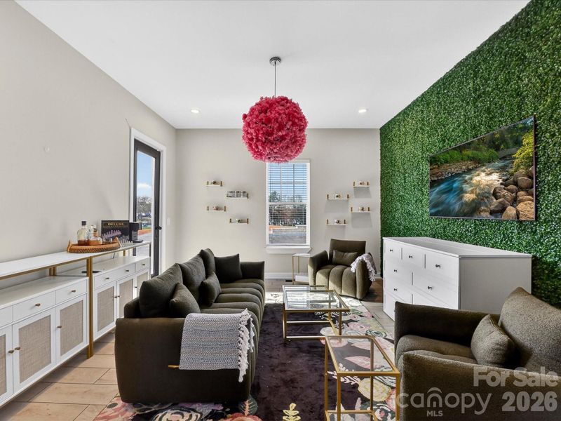 Stylish flex space featuring cozy seating space, a statement accent wall, and modern decor perfect for lounging or entertaining.