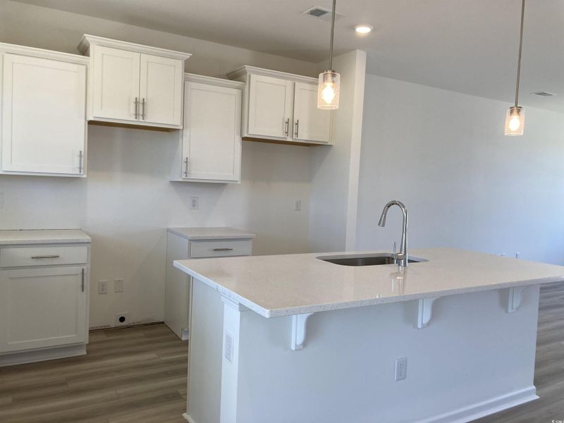 Kitchen featuring white cabinets, a breakfast bar area, pendant lighting, and recessed lighting