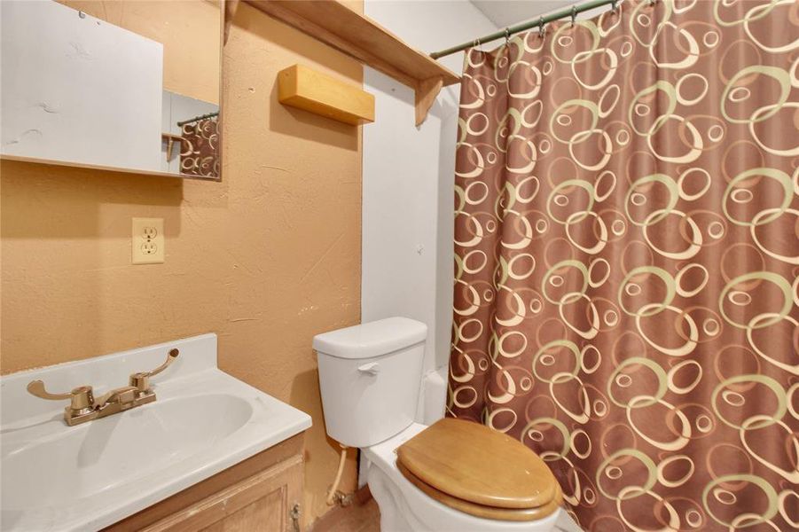 Full bathroom with vanity, a textured wall, and curtained shower Full bathroom with vanity, a textured wall, and curtained shower