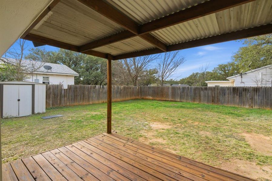 Wooden deck featuring a storage unit and a fenced backyard Wooden deck featuring a storage unit and a fenced backyard