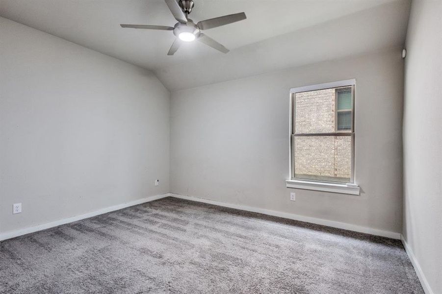 Carpeted spare room featuring lofted ceiling and a ceiling fan Carpeted spare room featuring lofted ceiling and a ceiling fan