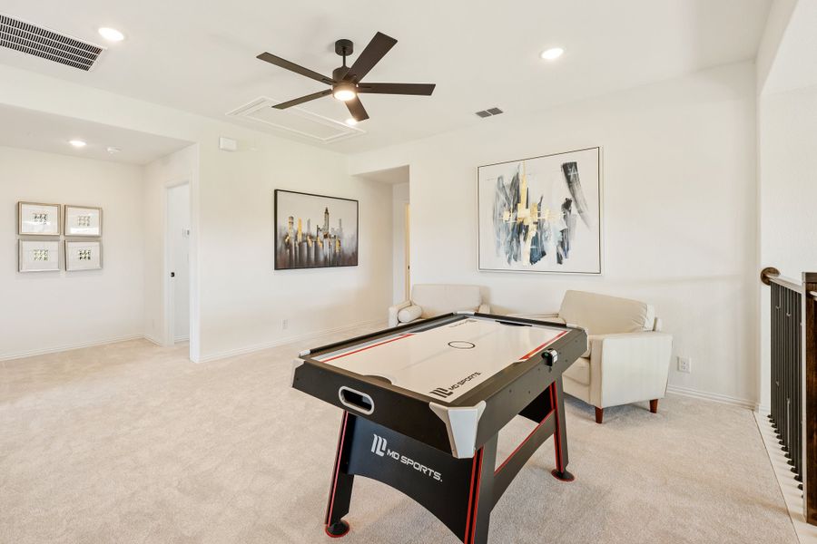 Game room with air hockey table, ceiling fan, carpet flooring, and wall art near staircase landing