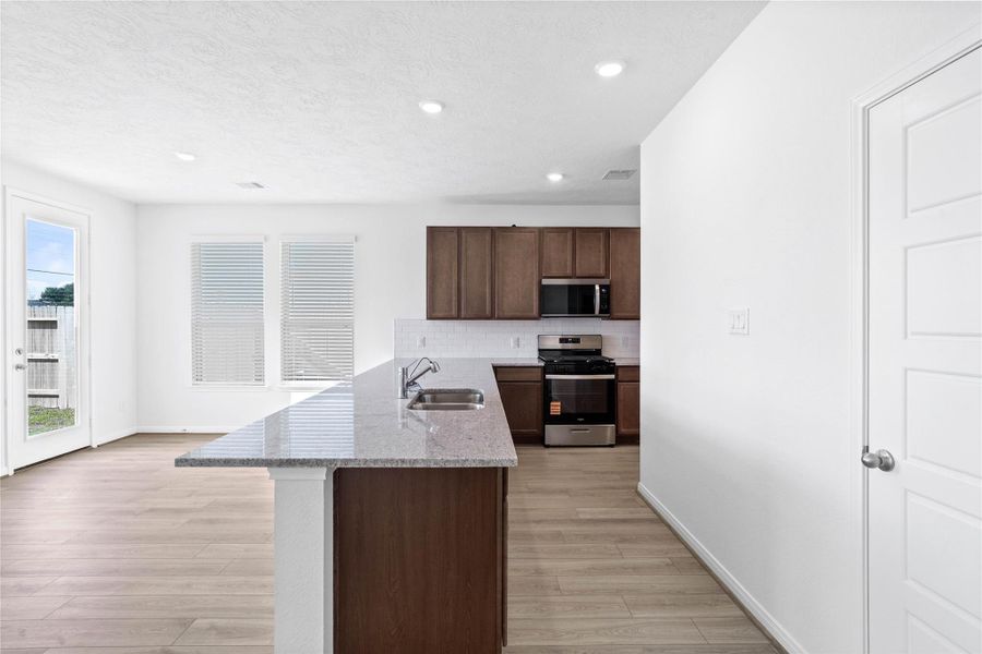 As you enter the Great Room, you are greeted by this spacious kitchen with a long granite countertop in Summit White and added breakfast bar.
