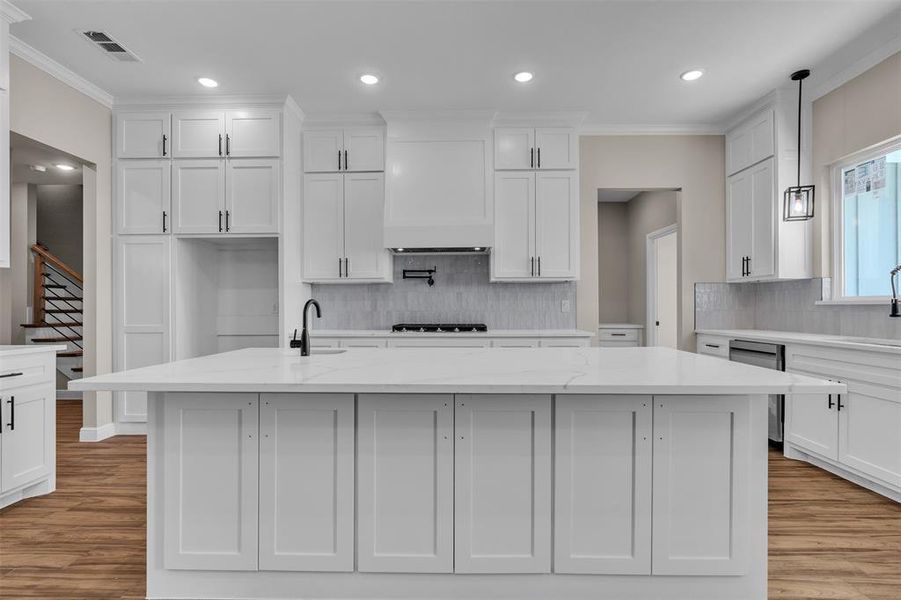 Kitchen with ornamental molding, decorative backsplash, recessed lighting, light wood-type flooring, and white cabinets Kitchen with ornamental molding, decorative backsplash, recessed lighting, light wood-type flooring, and white cabinets