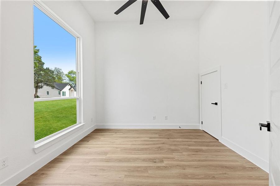 Bright interior space featuring a large window, light-colored flooring, and a ceiling fan Bright interior space featuring a large window, light-colored flooring, and a ceiling fan