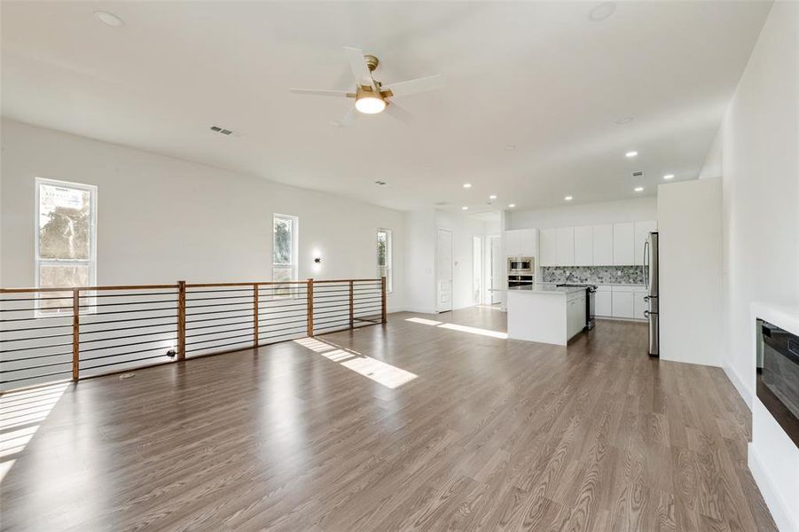 Unfurnished living room with recessed lighting, light wood-style flooring, a ceiling fan, and plenty of natural light Unfurnished living room with recessed lighting, light wood-style flooring, a ceiling fan, and plenty of natural light