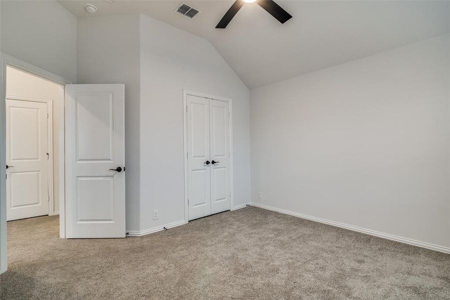 Upstairs bedroom featuring ceiling fan, a closet, light carpet, and vaulted ceiling