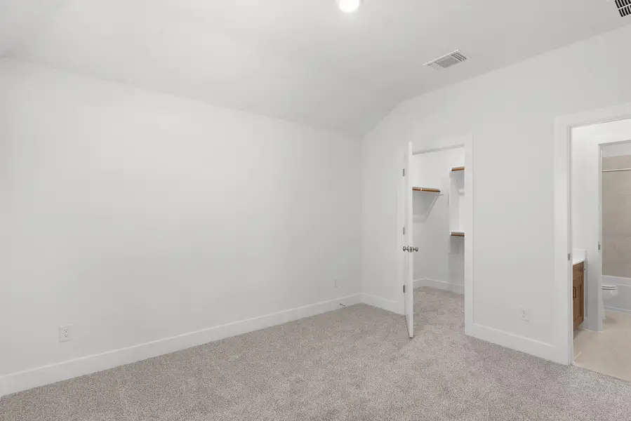 An inviting secondary bedroom features a spacious walk-in closet and convenient en-suite bathroom access.