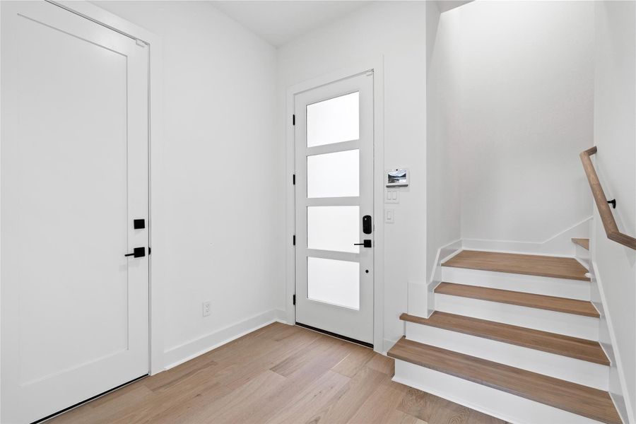 A study in simplicity and intention, the entryway unfolds with quiet elegance—anchored by wide-plank white oak floors and crisp architectural lines. Just off the foyer, a versatile first-floor suite awaits, equally suited as a private guest retreat or a serene home office. This is a space designed not just for arrival, but for immediate ease.
