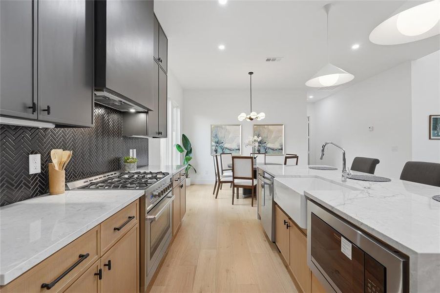 Modern kitchen featuring light wood-finish flooring, dark upper cabinetry, natural wood lower cabinetry, and light countertops Modern kitchen featuring light wood-finish flooring, dark upper cabinetry, natural wood lower cabinetry, and light countertops