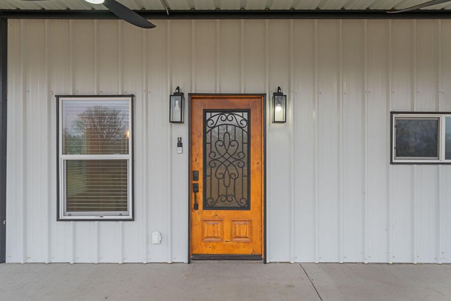 A beautiful custom wood front door with a decorative glass insert provides a warm welcome.