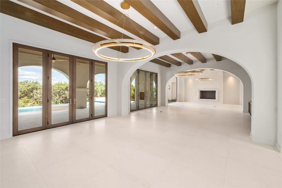 Great Room defined with low arches, beams and modern chandeliers