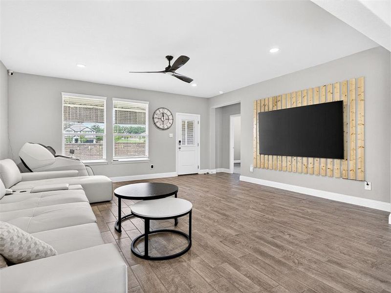 Spacious living area featuring wood-finish flooring, recessed lighting, and a contemporary ceiling fan Spacious living area featuring wood-finish flooring, recessed lighting, and a contemporary ceiling fan