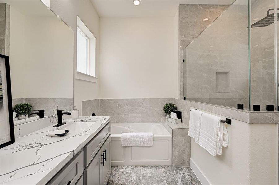 This bathroom features a modern design with marble countertops and floor tiles. It includes a dual-sink vanity, a spacious bathtub, and a glass-enclosed shower. Natural light streams in through a window, enhancing the clean and elegant atmosphere.