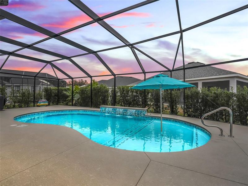 Pool area with expanded patio space, shallow shelf with umbrella, and three waterfalls