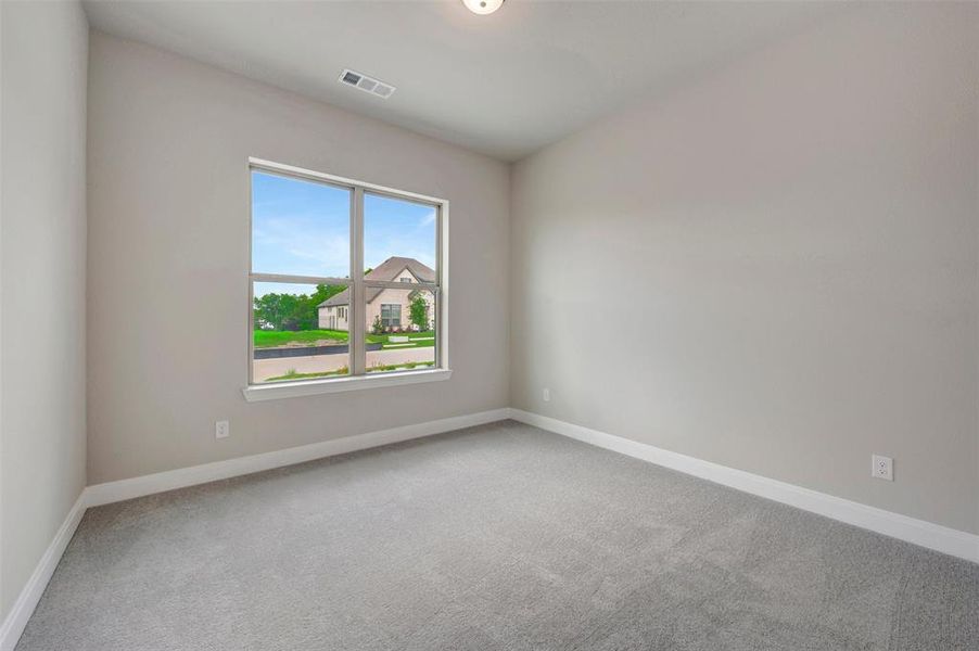 Neutral-toned room featuring a large window, light gray carpeting, crisp white baseboards, and a ceiling light fixture