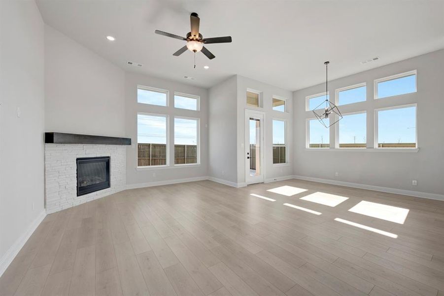 Unfurnished living room with a stone fireplace, ceiling fan, recessed lighting, and light wood-style floors Unfurnished living room with a stone fireplace, ceiling fan, recessed lighting, and light wood-style floors