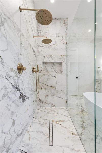 Bathroom with a marble finish shower and a freestanding bath