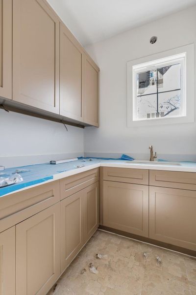 Laundry room in progress featuring painted cabinetry, patterned tile, and a utility sink with integrated washboard and Delta Cassidy faucet. Washer and dryer will sit just to the left of this cabinetry (not pictured).