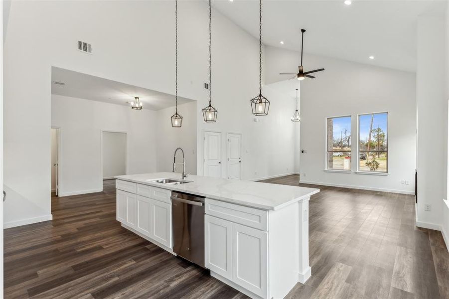 Kitchen with sink, hanging light fixtures, an island with sink, white cabinets, and stainless steel dishwasher