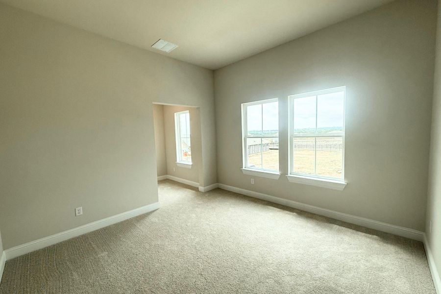 Carpeted interior space with neutral wall paint, two large windows, white trim, and a recessed entryway Carpeted interior space with neutral wall paint, two large windows, white trim, and a recessed entryway