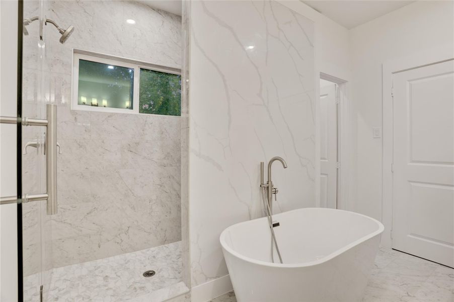 Spa-style walk in shower and soaking tub framed with elegant marble finishes.