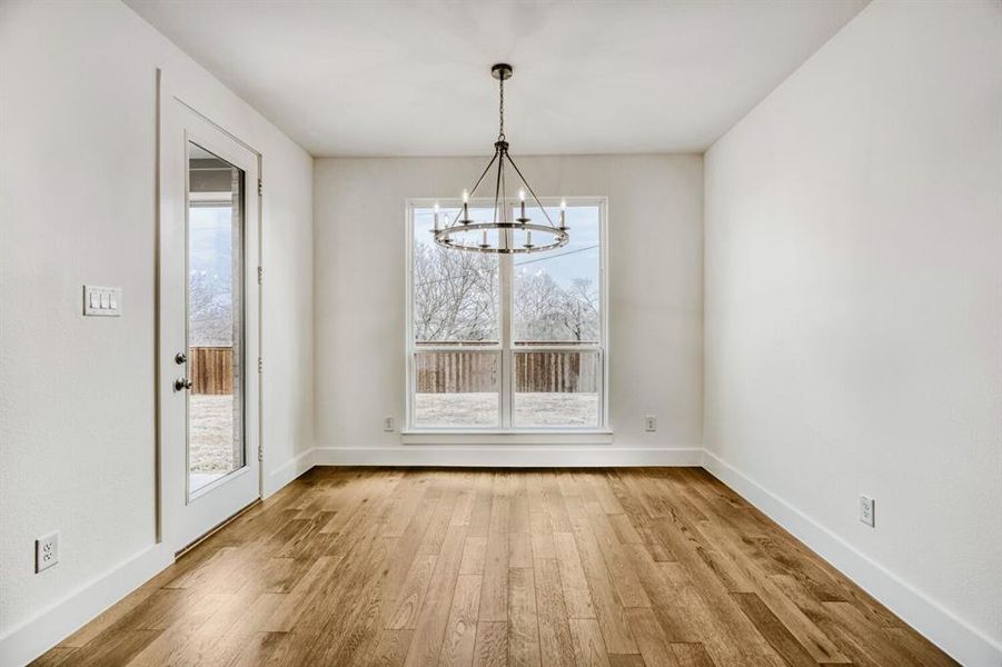 Unfurnished dining area with light wood-style flooring and suspended lighting