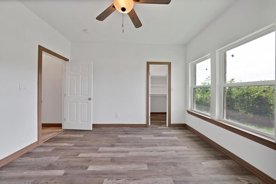Unfurnished bedroom featuring a spacious closet, light wood-type flooring, and ceiling fan