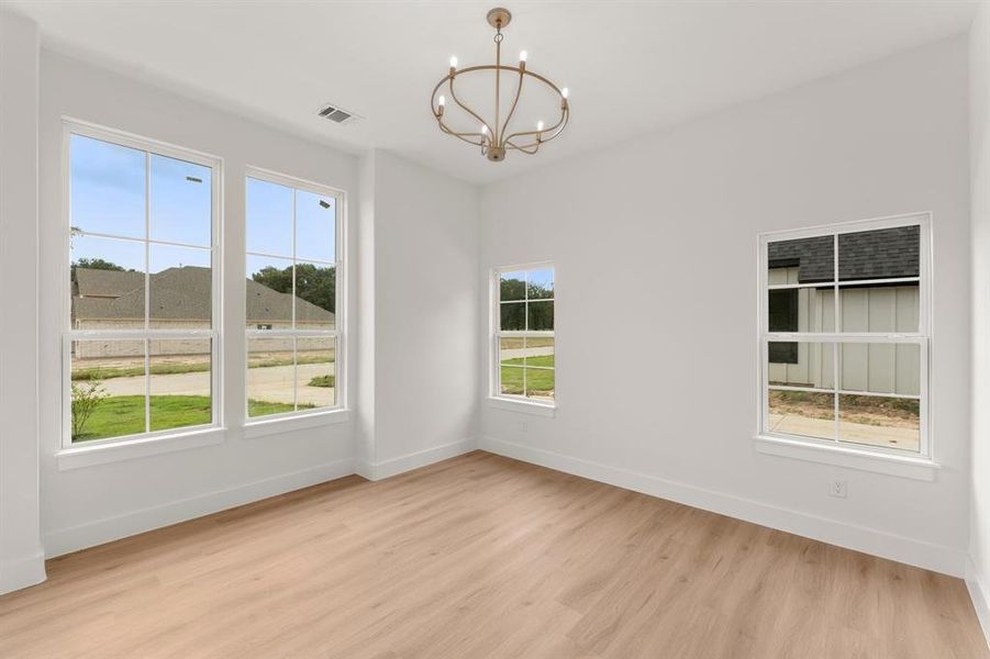 Spare room with light wood finished floors and a chandelier