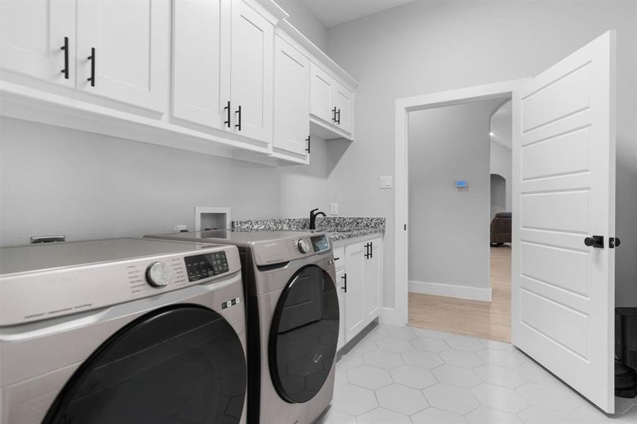 Laundry area featuring cabinets, light tile floors, washer hookup, and washing machine and clothes dryer