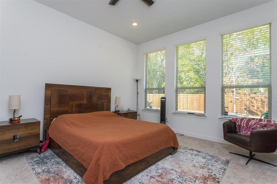 Bedroom featuring light carpet, ceiling fan, and vaulted ceiling