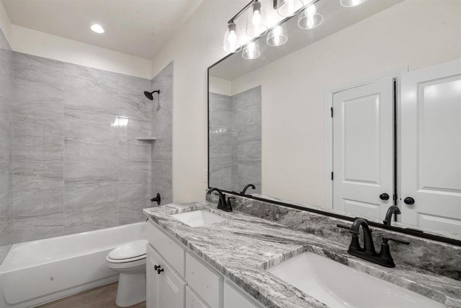 Full bathroom featuring toilet, tiled shower / bath combo, and vanity