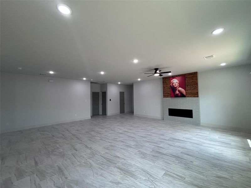 Unfurnished living room featuring recessed lighting, a large fireplace, and a ceiling fan Unfurnished living room featuring recessed lighting, a large fireplace, and a ceiling fan