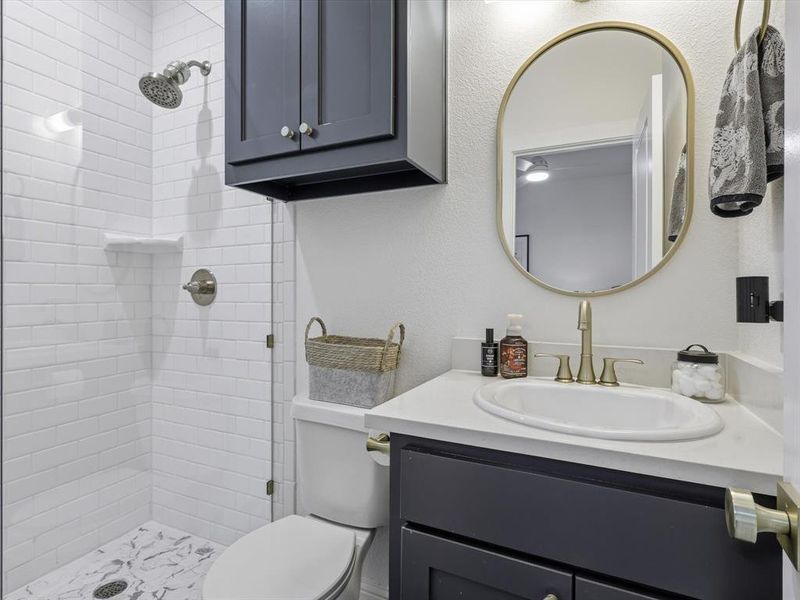 Full bathroom featuring vanity, a textured wall, and a stall shower