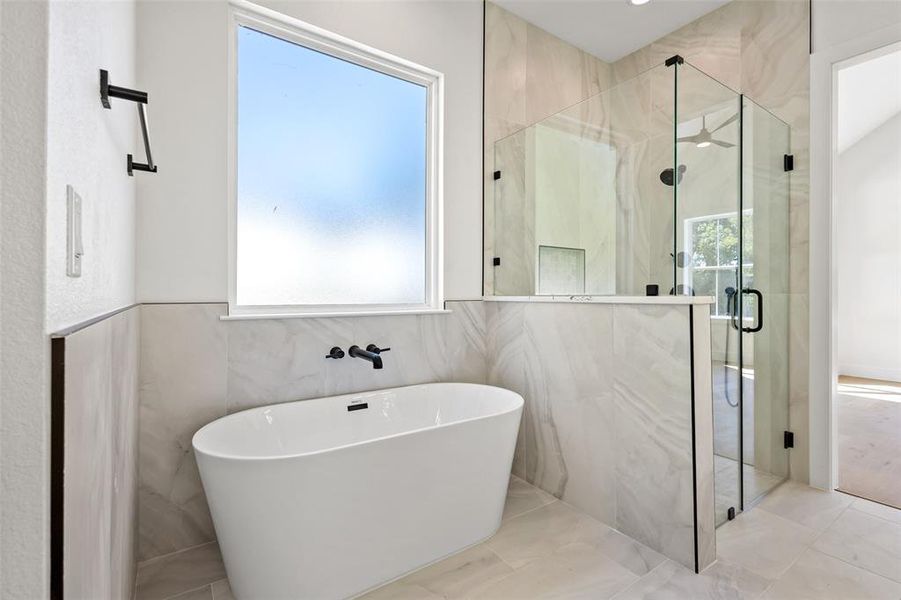 Full bathroom with a freestanding bath, a marble finish shower, and tile walls Full bathroom with a freestanding bath, a marble finish shower, and tile walls