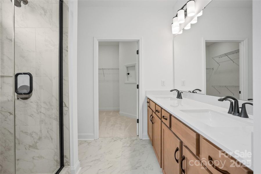 Luxurious primary bathroom features dual sinks and walk-in shower with a tiled bench seat