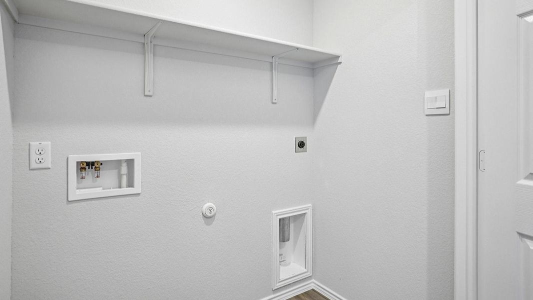 A dedicated laundry space provides practical utility with an integrated shelf. A dedicated laundry space provides practical utility with an integrated shelf.