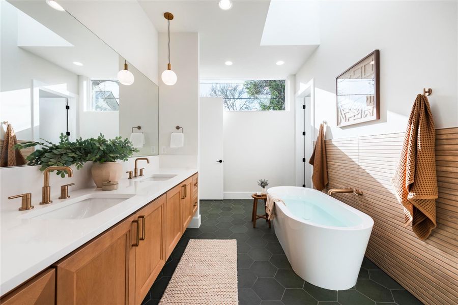 Full bathroom featuring double vanity, a soaking tub, a sink, and tile patterned flooring